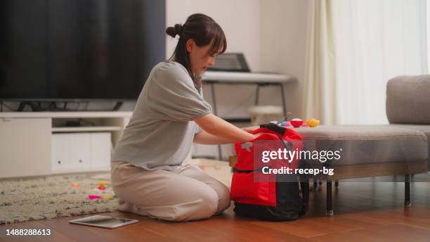 mujer preparando bolsa de emergencia en casa - evacuación fotografías e imágenes de stock