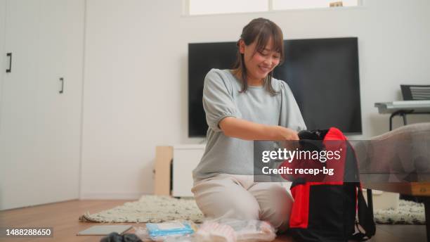 woman preparing emergency bag at home - evacuation plan stock pictures, royalty-free photos & images