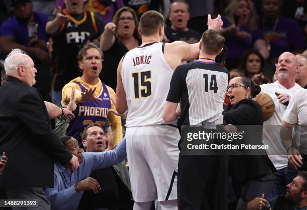 Nikola Jokic of the Denver Nuggets reaches for the basketball after pushing off Phoenix Suns owner Mat Ishbia during the first half of Game Four of...