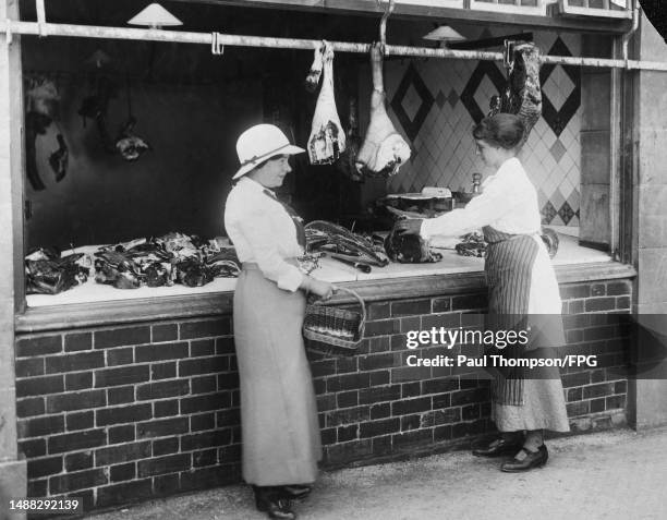 Miss Lee cutting into a forerib of beef for a waiting customer at her father's butcher shop in Barnstaple in Devon, England, circa 1916. Owing to...