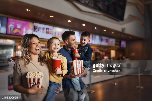 junge glückliche familie mit popcorn und getränken im kino. - film filmtechnik stock-fotos und bilder