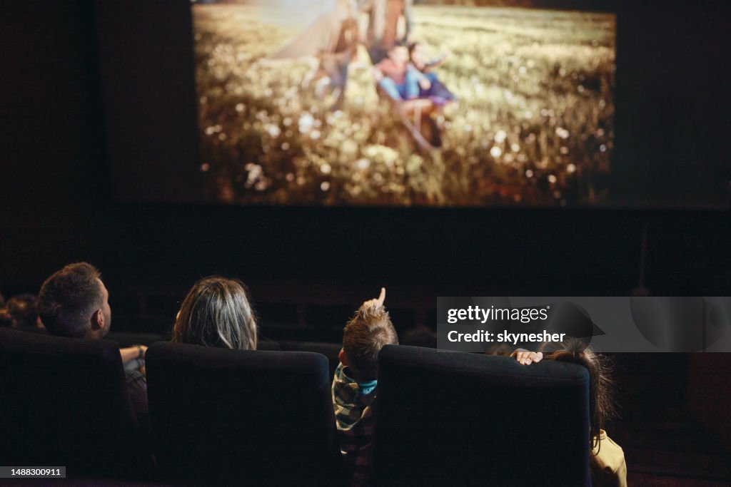 Back view of a family watching a movie in cinema.