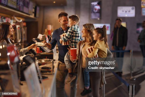 happy family buying movie tickets in cinema. - movie counter stock pictures, royalty-free photos & images