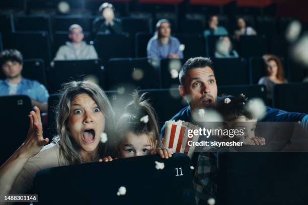 ängstliche familie, die sich einen horrorfilm im kino ansieht. - horror girls stock-fotos und bilder