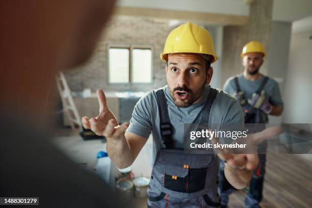 displeased manual worker arguing with his colleague at renovating house. - bad communication stock pictures, royalty-free photos & images