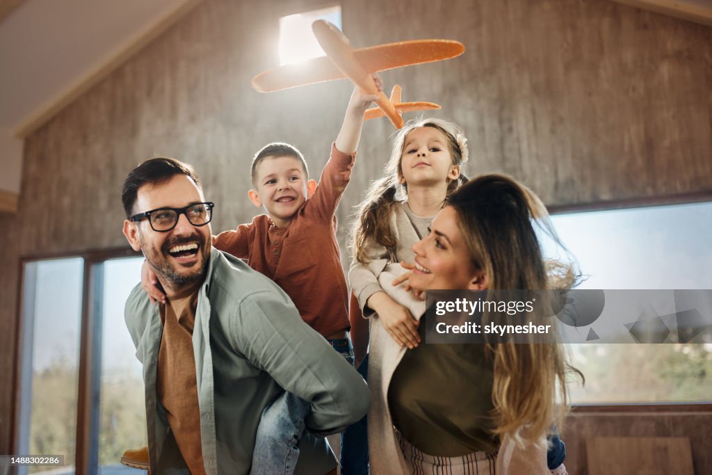 Happy family having fun while piggybacking in new home.