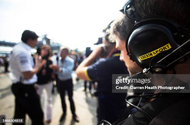 Close-up photograph of a BBC TV sound engineer's headphones as he works with his TV camera holding cameraman as the defocussed flower patterned shirt...