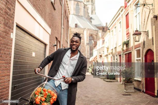 handsome black man traveller biking in delft on a sunny day - delft stock pictures, royalty-free photos & images