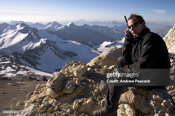 a mountaineer making a satellite telephone call high on aconcagua. - mount aconcagua stock pictures, royalty-free photos & images