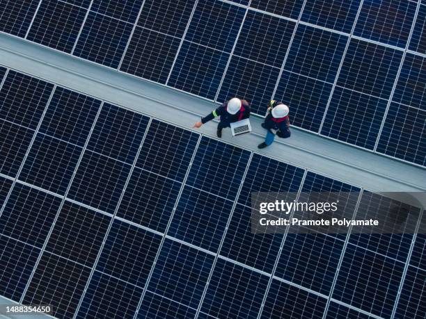 aerial view of engineer or technician working on checking equipment in solar power plant on the roof of an industrial factory. concept of installing solar cells on the roof. - energia renovável imagens e fotografias de stock