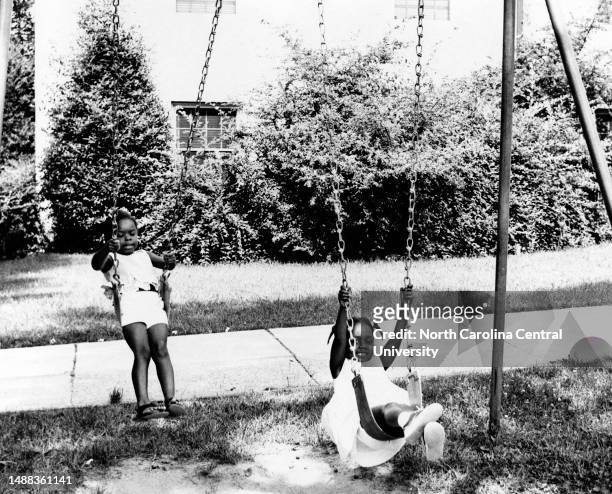 Two little girls playing on swings during summer activities at North Carolina College.