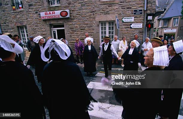 a troupe of traditional breton dancers in their black costumes with white headdresses, performing in the street - coiffe bretonne photos et images de collection
