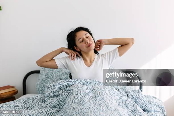 young teenager latin american waking up after sleeping on bed - awake day stockfoto's en -beelden