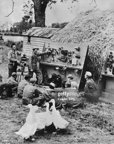 Gaggle of geese wander into the frame as American military officer Sgt James H Hobbs stands beside a mock-up of the electrical system of an American...