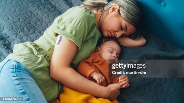 young mother with diabetes and baby napping at home - continuous glucose monitor stock pictures, royalty-free photos & images