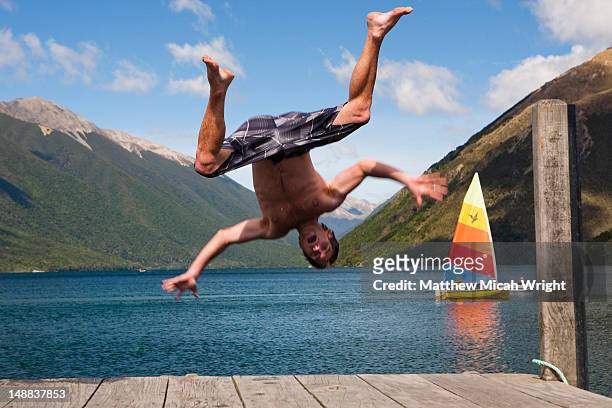 lake rotoiti is lake in the tasman region of new zealand. it is a mountain lake within in the nelson lakes national park. this man jumps off the end of the bridge into the cold water - nelson lakes national park stock pictures, royalty-free photos & images