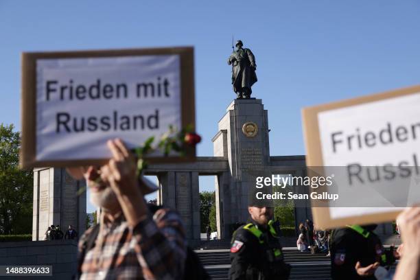 Leftist demonstrators hold up signs that read: "Peace with Russia" as the statue of a Soviet soldier looms behind at the Soviet World War II memorial...