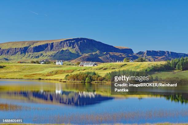 houses and mountains reflected in a shallow loch, quiraing, isle of skye, hebrides, scotland, united kingdom - hebriden inselgruppe stock-fotos und bilder