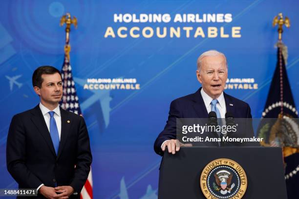 President Joe Biden speaks as Transportation Secretary Pete Buttigieg looks on at an announcement of new airline regulations in the South Court...
