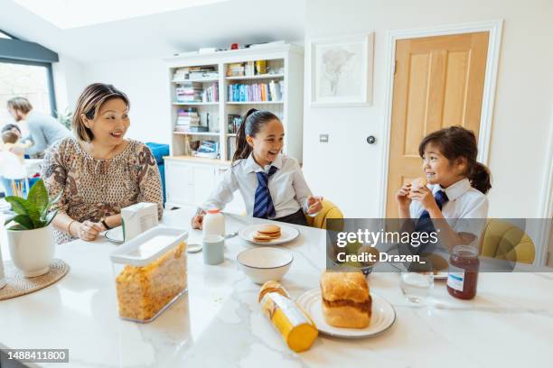 chinese family at home, girls eating breakfast before school - family eating stock pictures, royalty-free photos & images