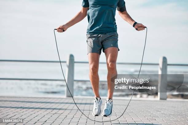 Jump rope, fitness and man by a sea promenade with training, sports and exercise equipment. Health, jumping and body wellness of a athlete doing cardio jump for active lifestyle by the ocean