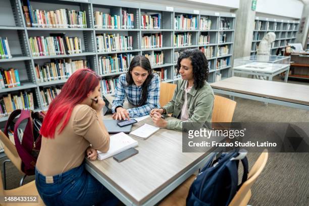student friends studying in the library at the university - reference book stock pictures, royalty-free photos & images