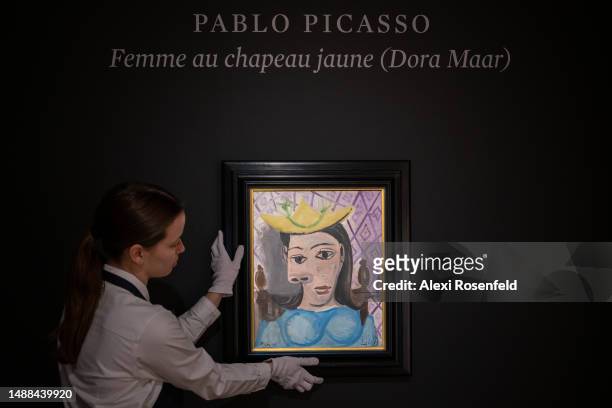 An art handler holds Pablo Picasso's "Femme au chapeau jaune " while on display during a press preview at Sotheby's on May 08, 2023 in New York City....