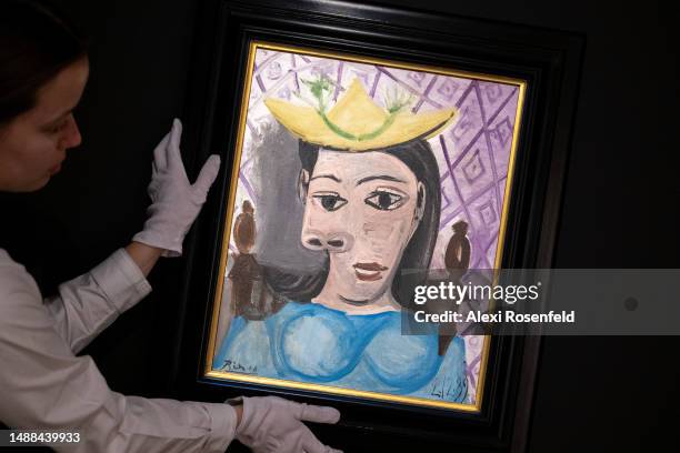 An art handler holds Pablo Picasso's "Femme au chapeau jaune " while on display during a press preview at Sotheby's on May 08, 2023 in New York City....