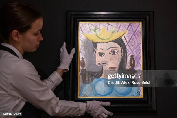 An art handler holds Pablo Picasso's "Femme au chapeau jaune " while on display during a press preview at Sotheby's on May 08, 2023 in New York City....