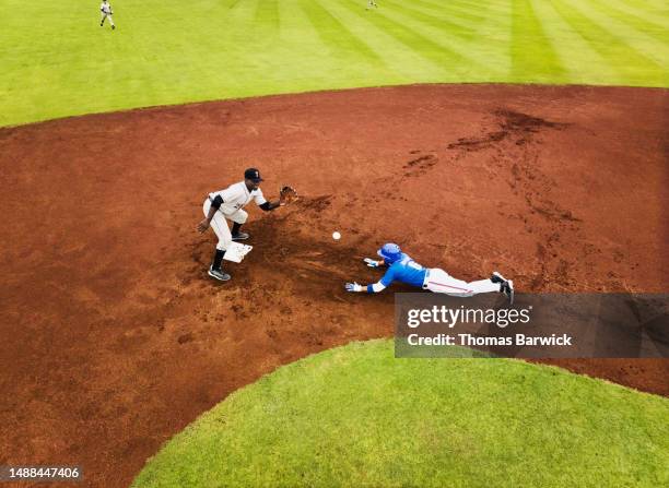 wide shot runner sliding into second during professional baseball game - baserunner stock pictures, royalty-free photos & images