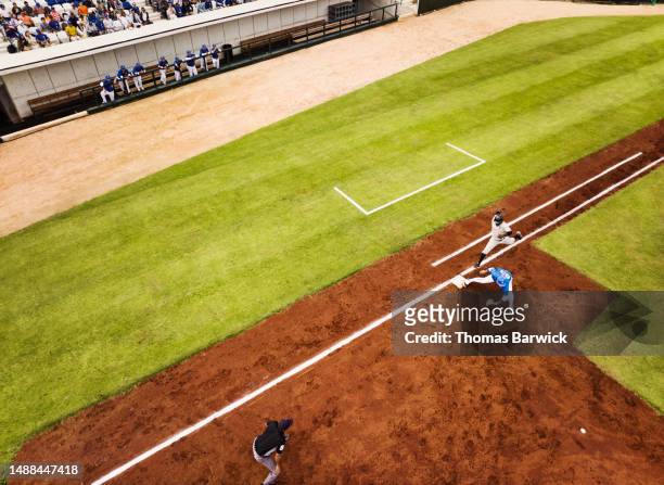 wide shot runner beating throw to first base during baseball game - baseball base stock-fotos und bilder
