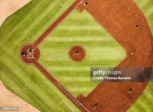 wide shot pitcher throwing to batter during professional baseball game - baseball stock-fotos und bilder