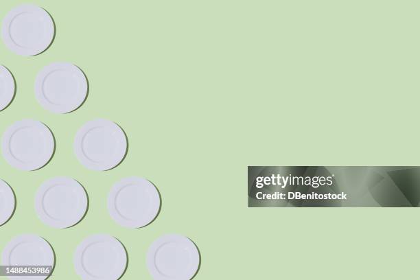 pattern of empty white plates, on the left side, on light green background. restaurant, food, catering, cooking, service, chef and haute cuisine concept. - tellerlift stock-fotos und bilder
