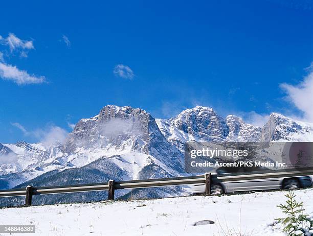 car driving past snowy mountain on uphill road. - uphill stock-fotos und bilder