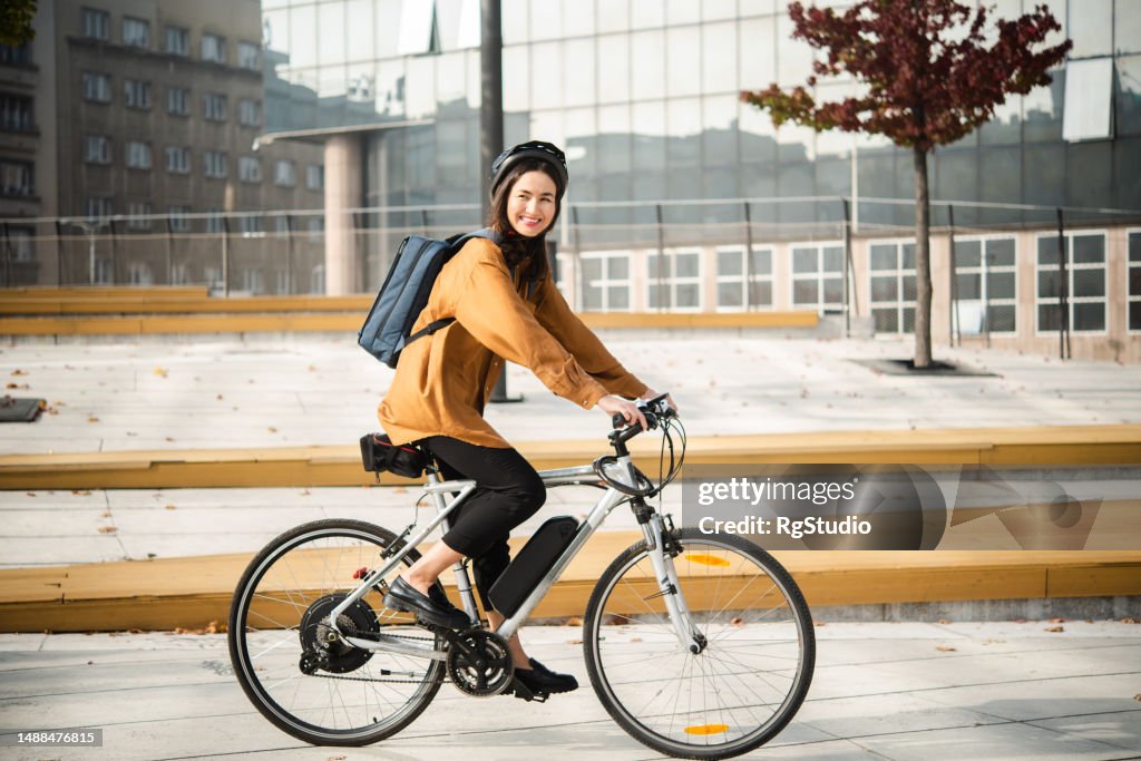 Asiatische Geschäftsfrau kommt mit ihrem E-Bike von der Arbeit zurück