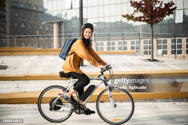 empresaria asiática regresa del trabajo en su bicicleta eléctrica - bicicleta fotografías e imágenes de stock