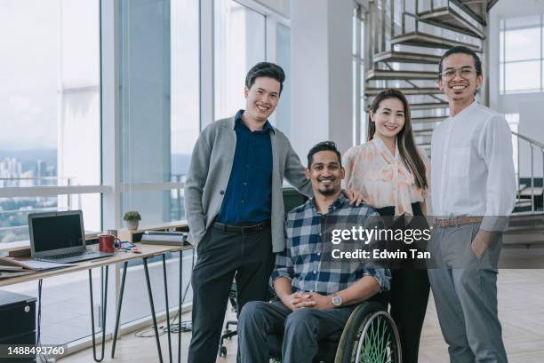 portrait indian white collar male worker in wheelchair and colleague in creative office workstation beside window - disability awareness stock pictures, royalty-free photos & images