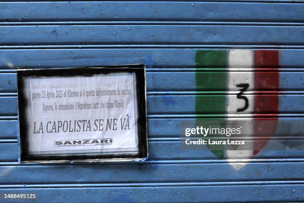 Blue colored gate with a graffiti of a shield and an ironic funeral poster with the inscription 'La capolista se ne va', the title of a famous chorus...