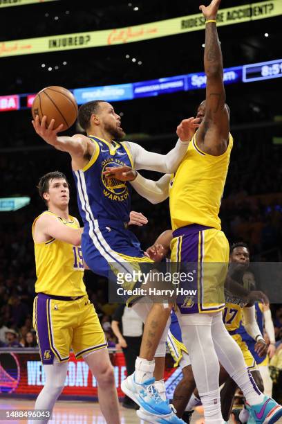 Stephen Curry of the Golden State Warriors shoots the ball against LeBron James and Austin Reaves of the Los Angeles Lakers during the third quarter...