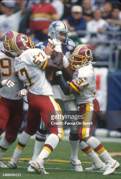 Ken Harvey of the Washington Redskins and Martin Bayless stop Jay Novacek of the Dallas Cowboys during an NFL football game October 2, 1994 at RFK...