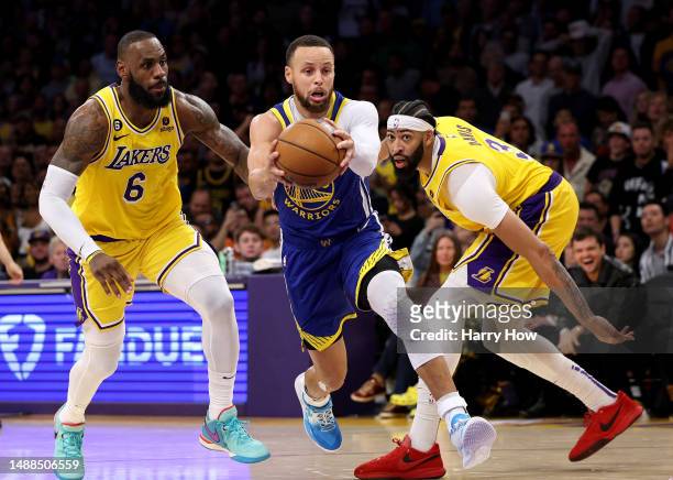 Stephen Curry of the Golden State Warriors dribbles between LeBron James and Anthony Davis of the Los Angeles Lakers during a 104-101 Lakers win in...