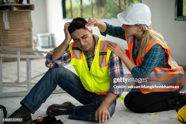 worker helping injured co-worker at construction site - building site accidents photos et images de collection