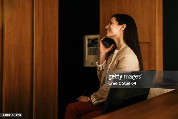 businesswoman sitting on the office desk, talking on a phone and smiling. copy space - bell telephone company stock pictures, royalty-free photos & images