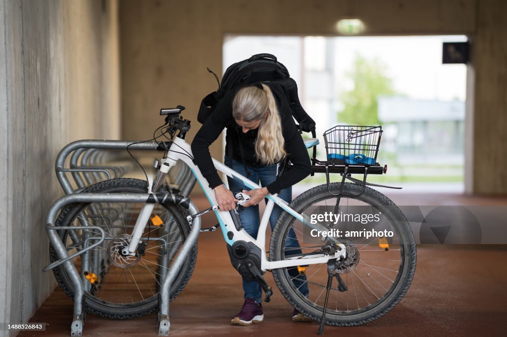 Frau schließt ihr Fahrrad am Bahnhof ab