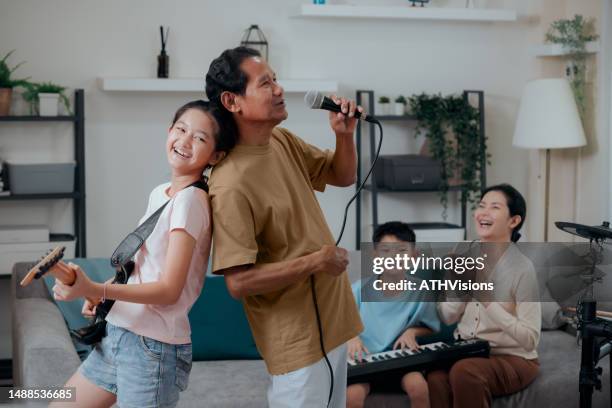 grandfather enjoy singing and playing music with family in the living room at home - asian musician stock pictures, royalty-free photos & images