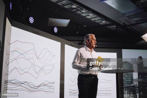 smiling senior male tech entrepreneur holding cue cards while giving speech at tech event - conference stage stock pictures, royalty-free photos & images