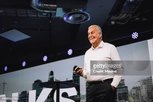 happy senior male tech entrepreneur standing with hand in pocket at tech event - visual aid stock pictures, royalty-free photos & images