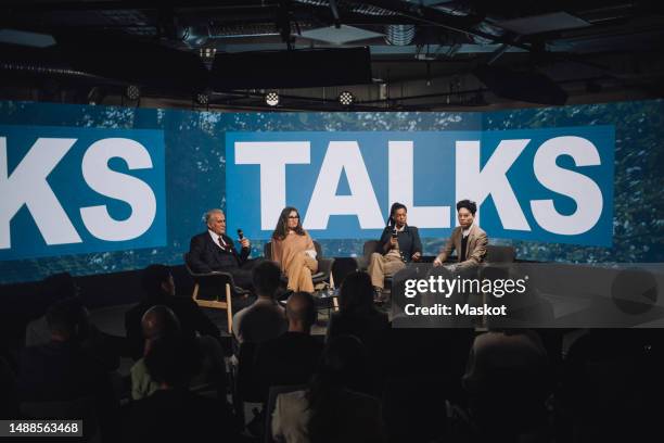 multiracial tech entrepreneurs sitting on stage during panel discussion at convention center - conference stage stock pictures, royalty-free photos & images