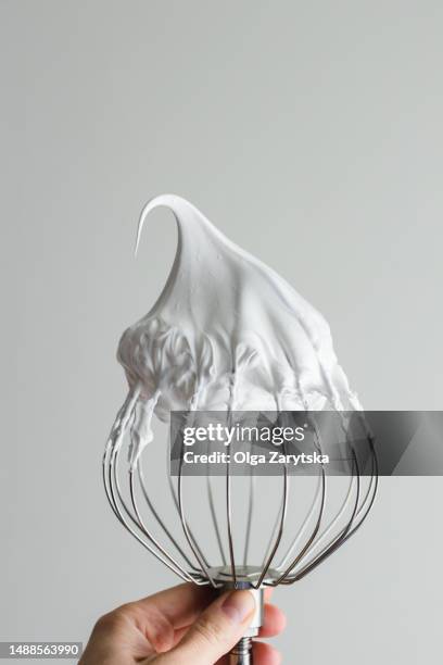hand holding whisk with whipped egg whites. - hand holding whisk stock pictures, royalty-free photos & images