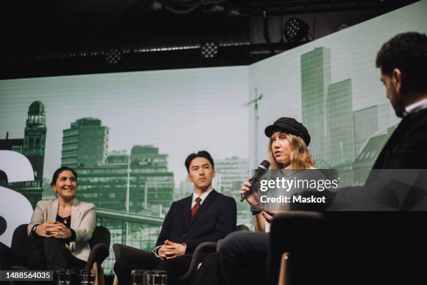 female tech entrepreneur discussing at tech event while sitting with colleagues during panel discussion at convention ce - conference speaker stock pictures, royalty-free photos & images